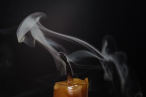 A Steam of faded candle looks like a jellyfish. On a black background.